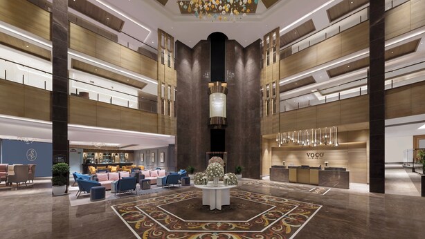 Un hall espacioso con mostrador de recepción central, zonas de estar y un candelabro decorativo.