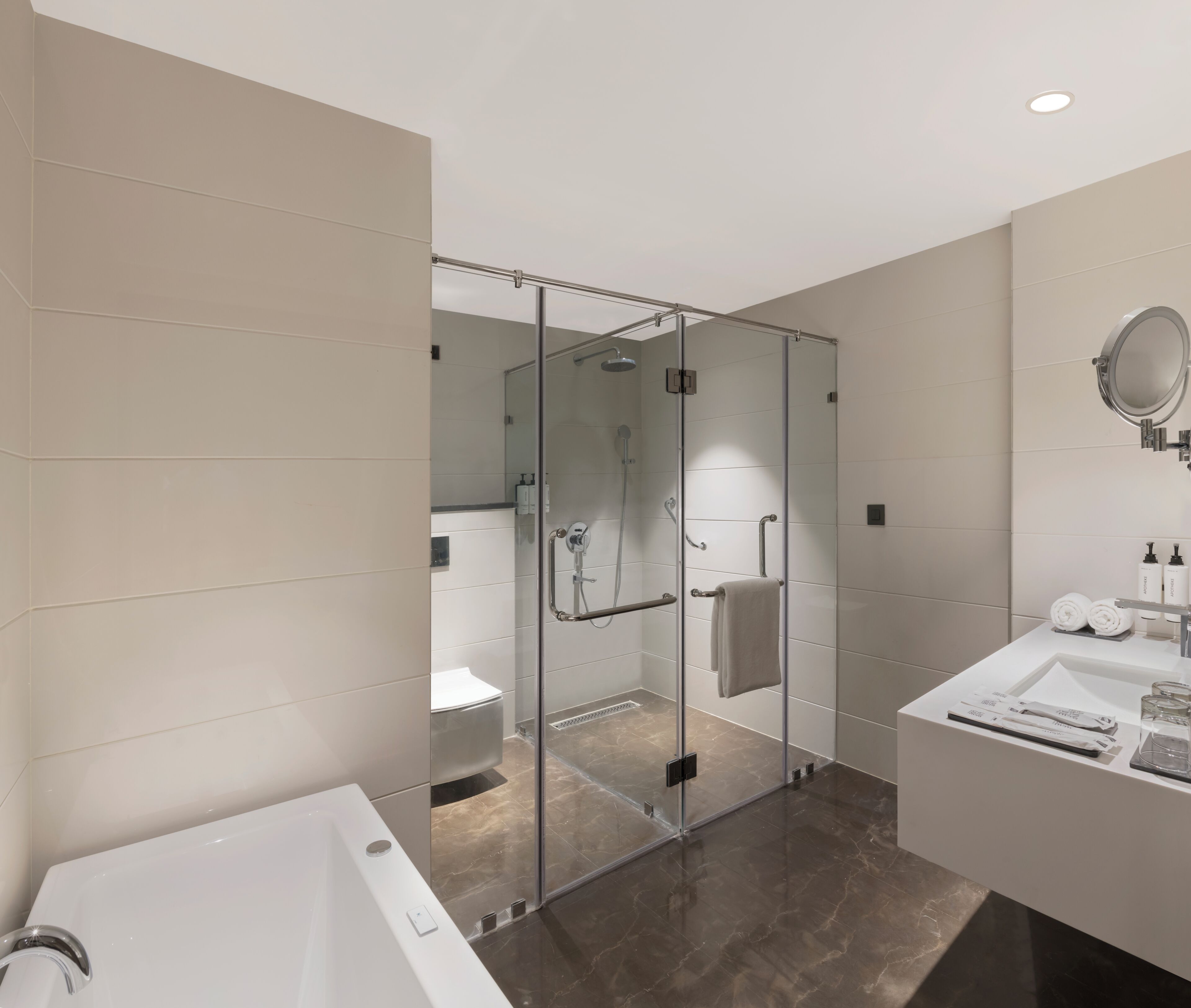 A modern bathroom with a glass-enclosed shower, a white sink, and a mirror.