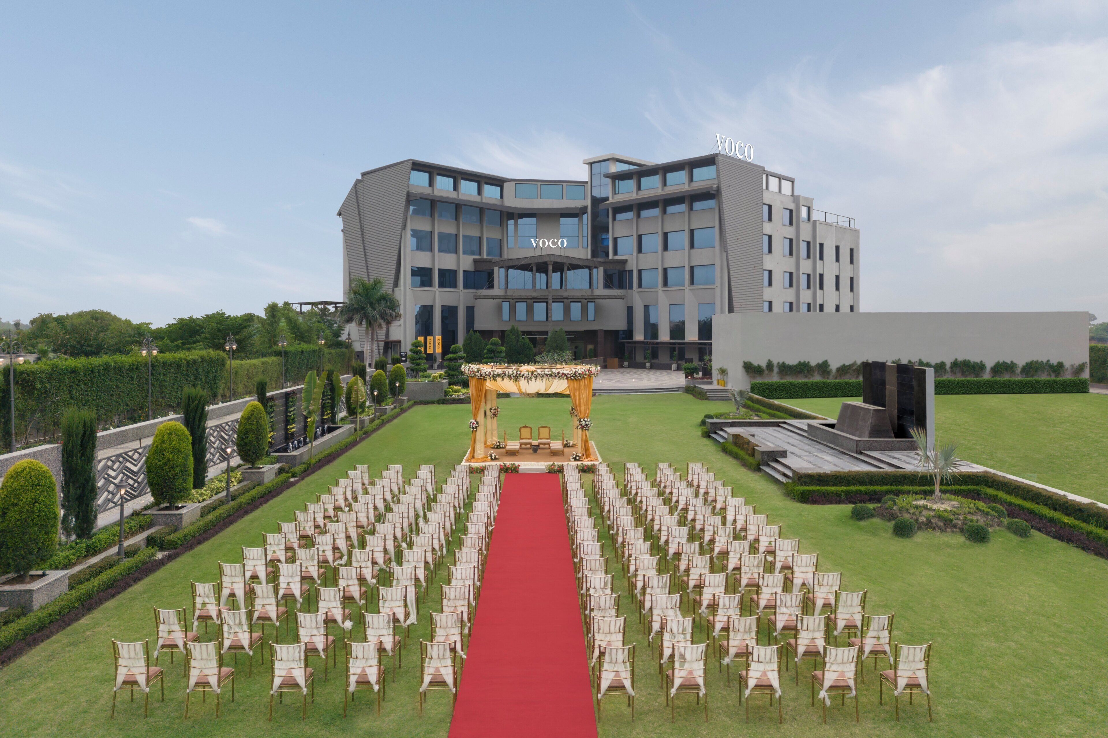 Un edificio con alfombra roja que conduce a un escenario, rodeado de filas de sillas.