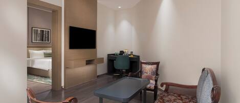 Habitación de hotel con cama, escritorio, televisor y dos sillas.