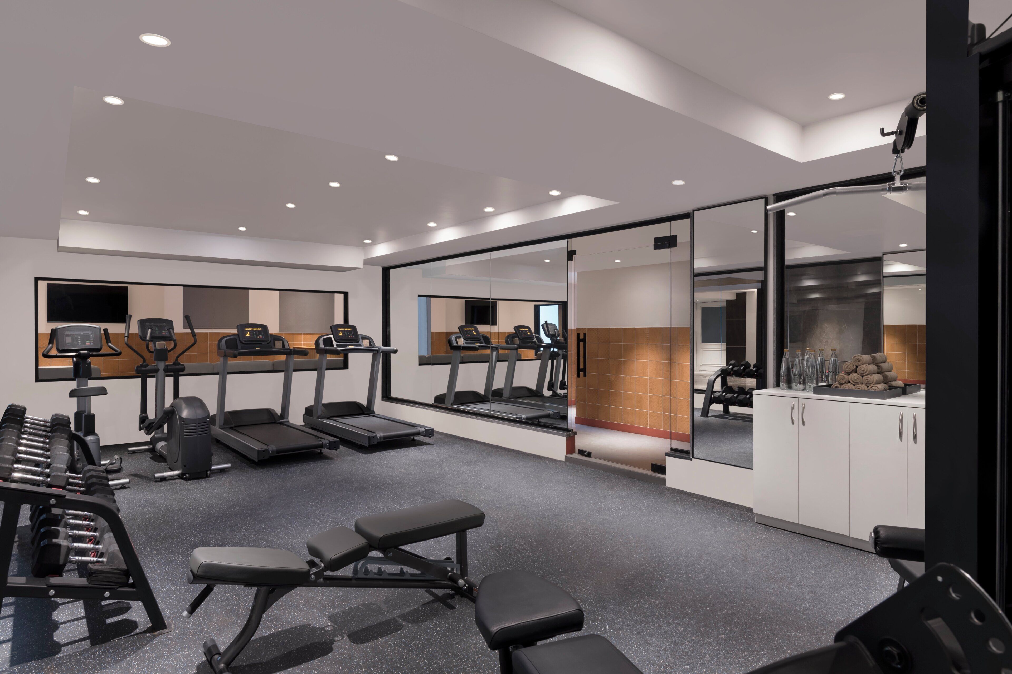 A modern gym with treadmills, weight machines, and benches.