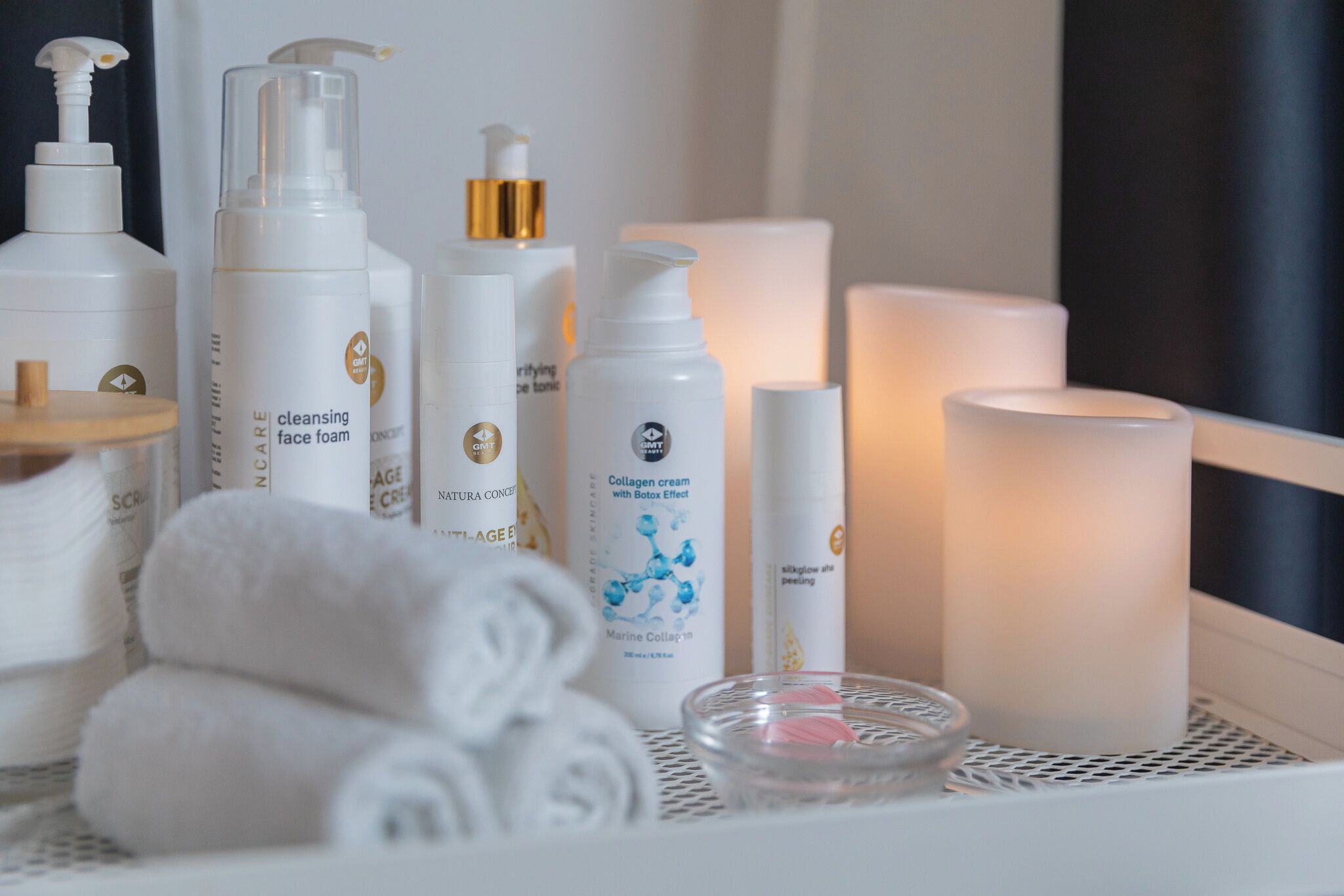 A selection of skincare products on a tray, including a cleansing foam, collagen cream, and a face toner.