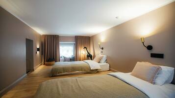 Habitación de hotel con dos camas, una ventana con cortinas, una estatua de jirafa y lámparas fijadas a la pared.