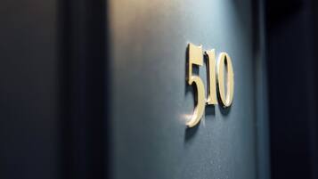 Lähikuva tummanvärisestä ovesta, jossa on kultaisilla kirjaimilla numero ”510” ja messinkinen ovenkahva.