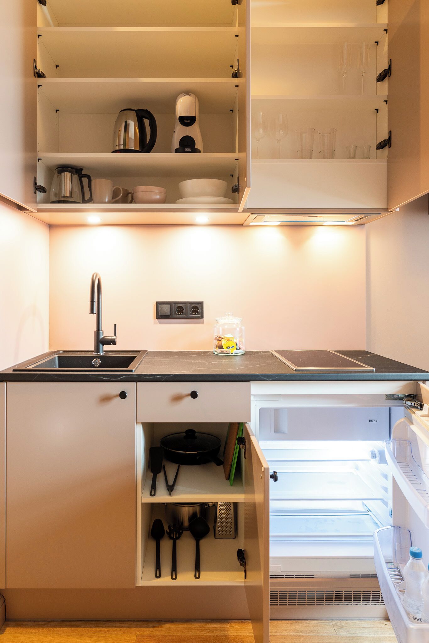 A compact kitchen with a built-in sink, a coffee maker, and a microwave.
