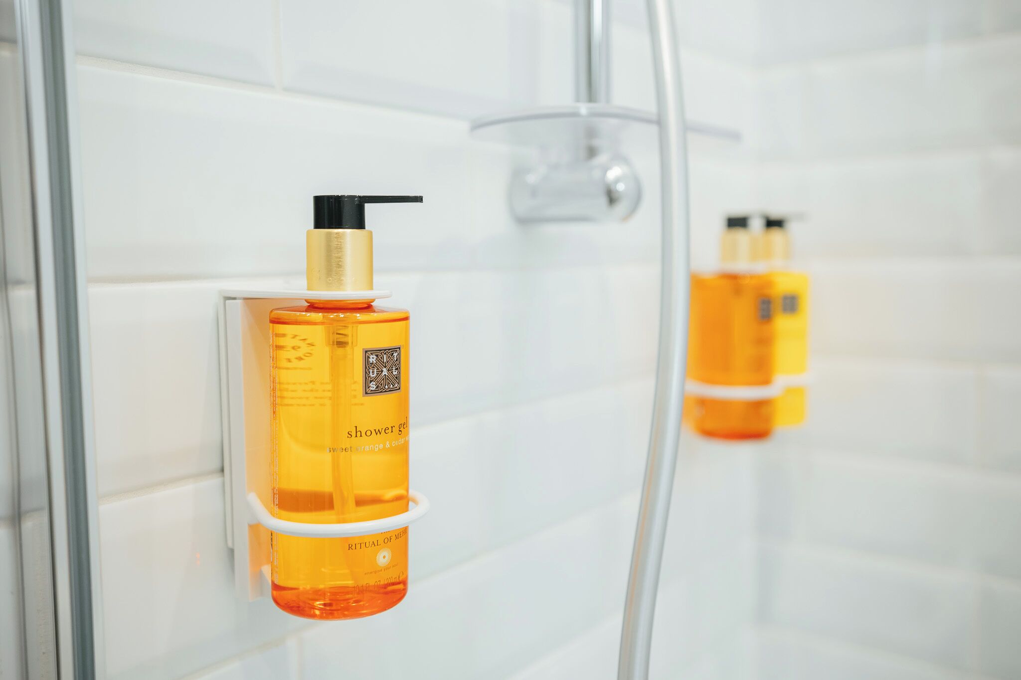 Un baño con ducha y dos botellas de gel de ducha en la pared.