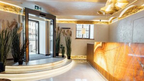 A modern lobby with a marble reception desk, potted plants, and a glass door entrance.