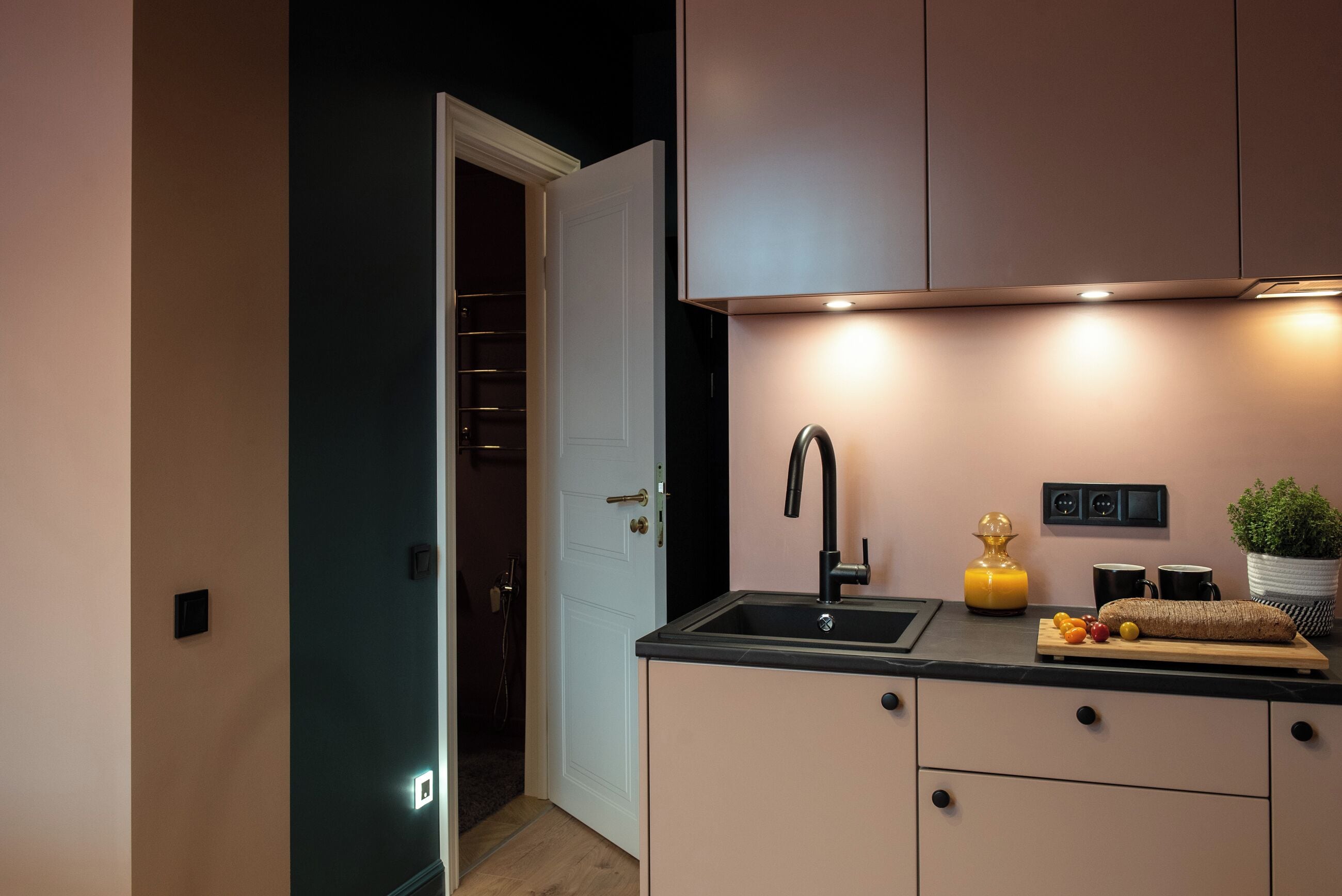 A modern kitchen with a built-in oven, a sink, and a countertop with a cutting board and fruits.