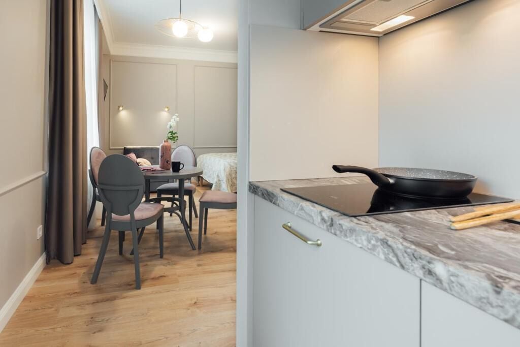 A modern kitchen with a marble countertop, a black frying pan, and a laptop.