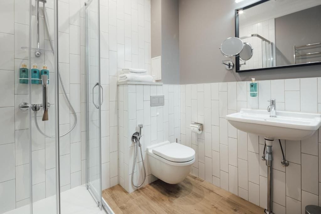 Un baño moderno con cabina de ducha de vidrio, inodoro blanco y lavabo con espejo arriba.