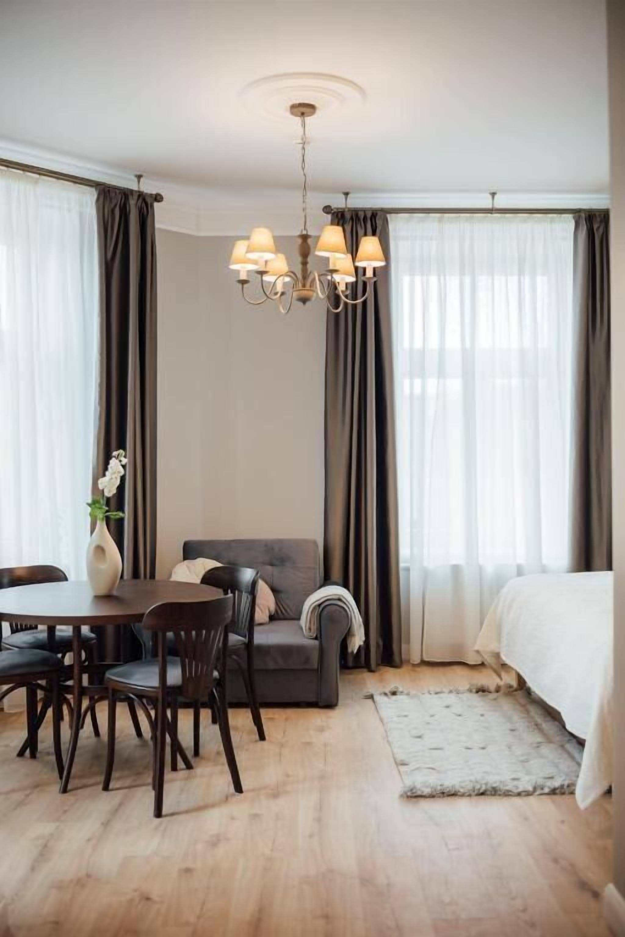 Een hotelkamer met een eethoek, een bank, een bed en een kroonluchter.
