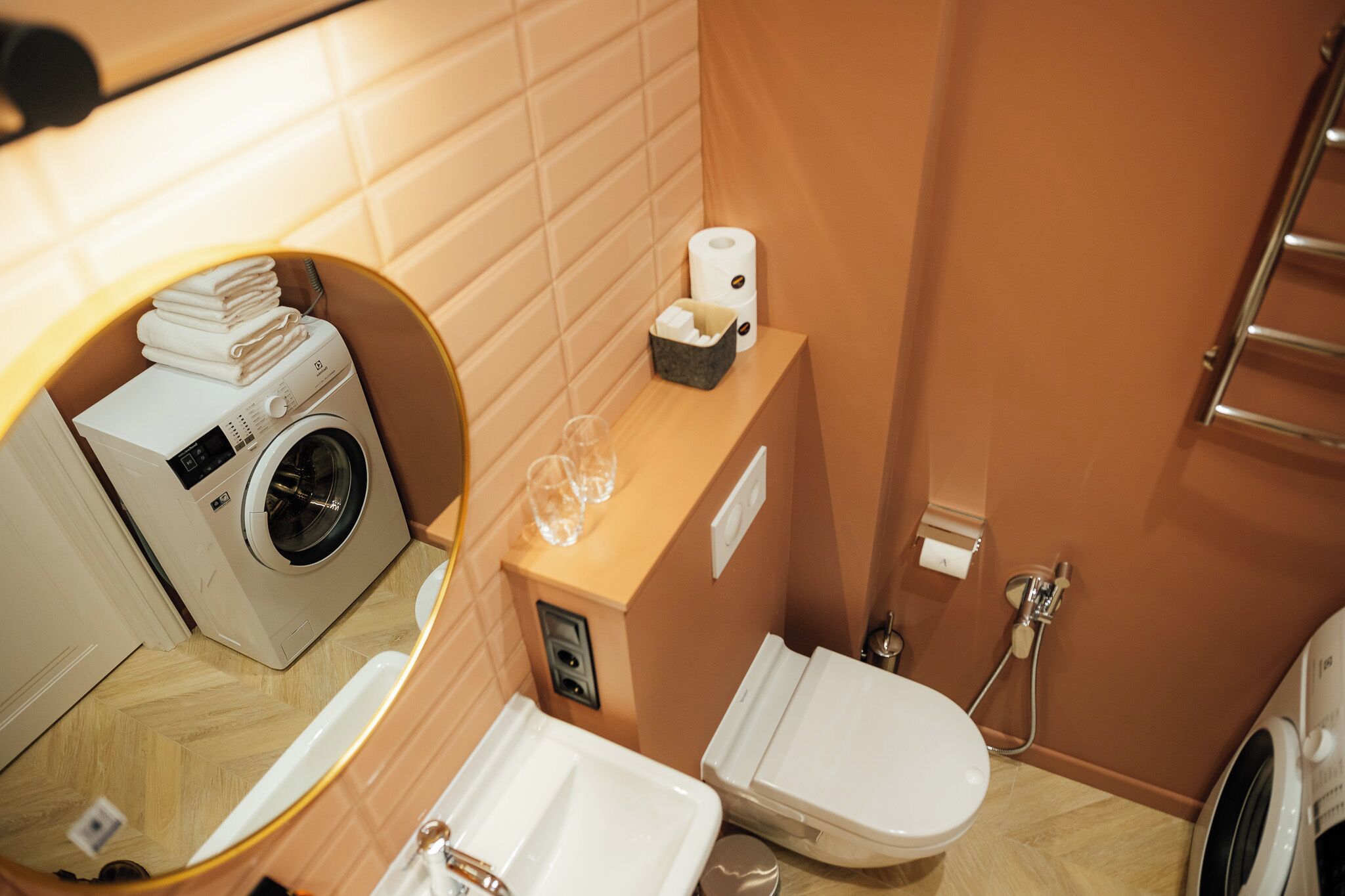 A compact bathroom with a washing machine, toilet, and sink.