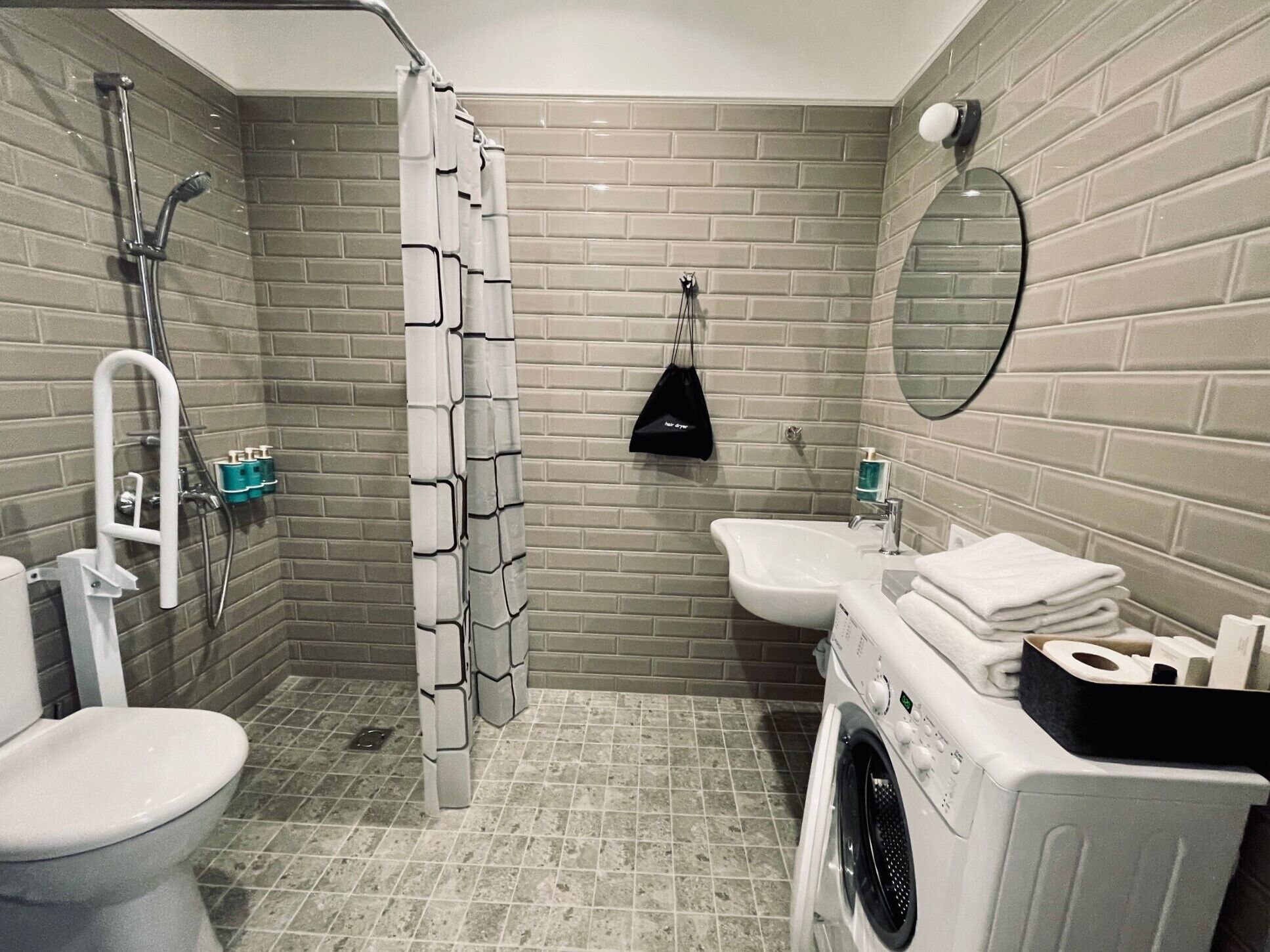 Ein kleines Badezimmer mit Dusche, Toilette, Waschbecken und Waschmaschine.