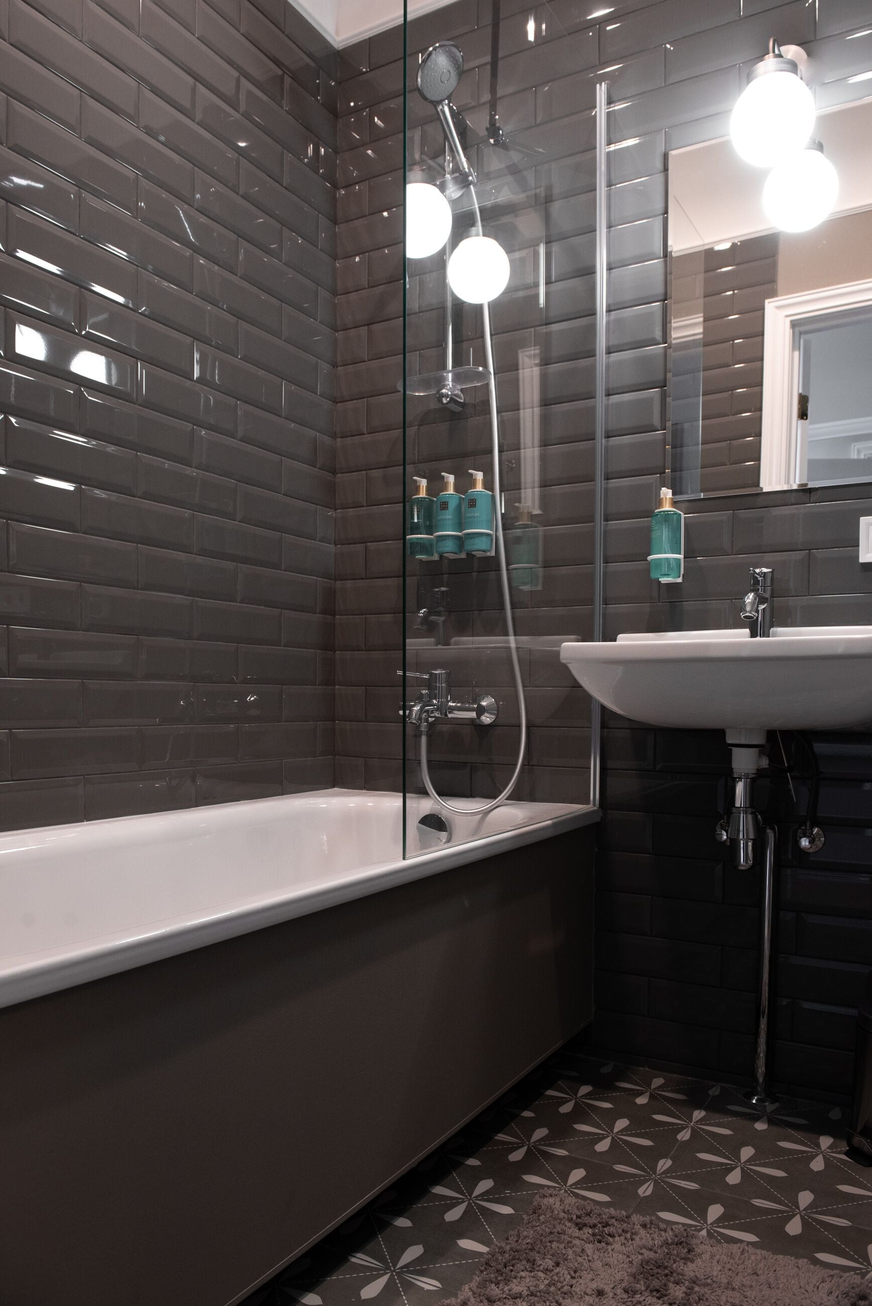 Une salle de bain moderne avec une douche à parois de verre, une baignoire blanche et un lavabo surmonté d’un miroir.