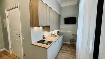 A compact kitchen with a built-in microwave, a sink, and a wooden countertop.