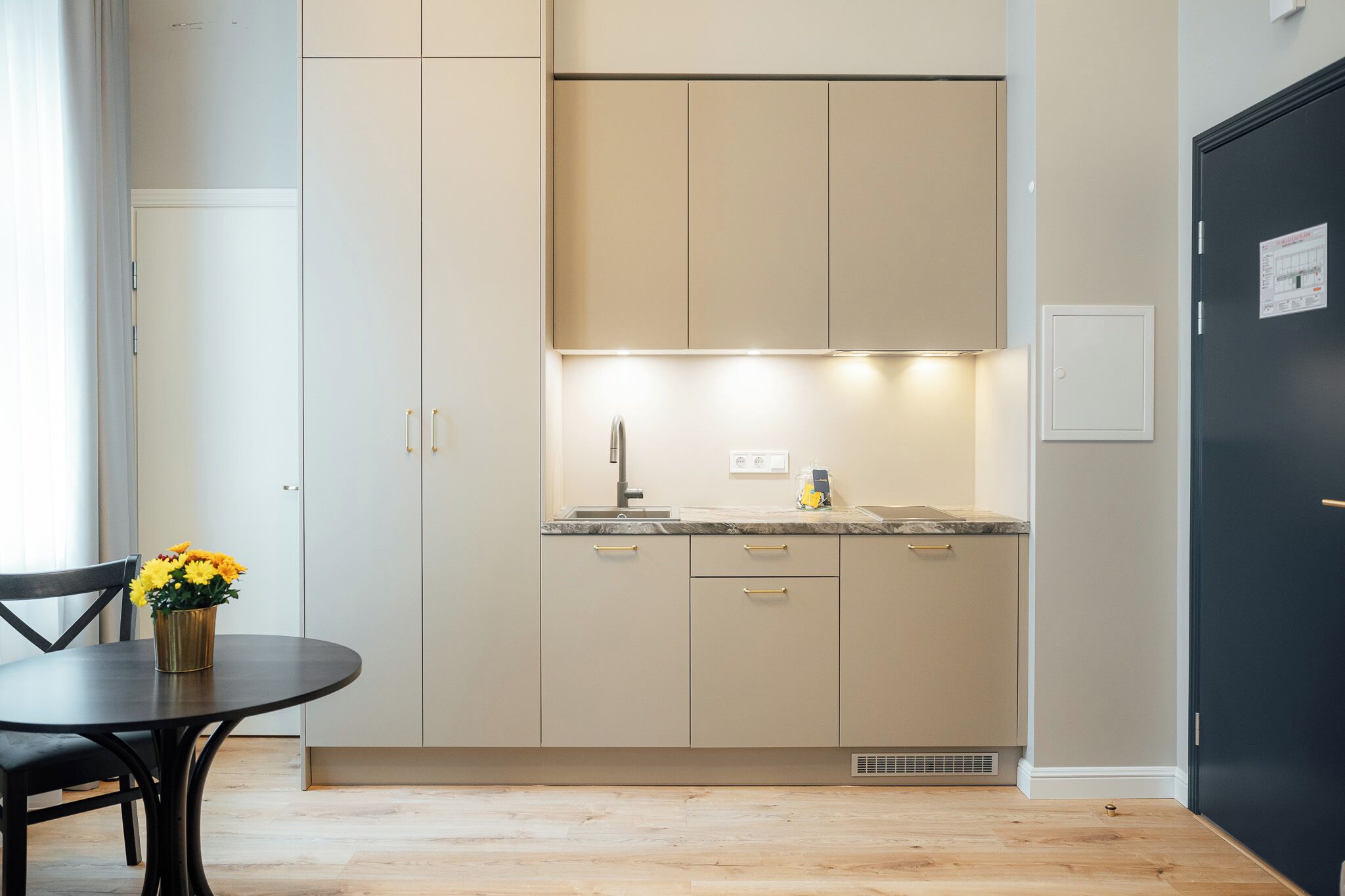 Una cocina moderna con una mesa de comedor y sillas, un jarrón de flores y una puerta negra.