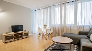Een moderne woonkamer met een flatscreen televisie, een eettafel met stoelen, een bank en een salontafel.