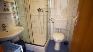 A bathroom with a glass-enclosed shower, a toilet, and a sink.