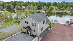 A two-story building with a covered front porch and a gravel driveway. - Great Lake Escape by PMR, 8BR Lakefront, Private Dock & Sun Deck, Sleeps 24 (Lake Harmony)