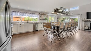 A modern kitchen with white cabinets, a stainless steel refrigerator, a dining table with chairs, and a built-in oven. - Great Lake Escape by PMR, 8BR Lakefront, Private Dock & Sun Deck, Sleeps 24 (Lake Harmony)
