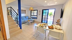 Una sala de estar moderna con una escalera, un comedor con desayuno y vistas al exterior.