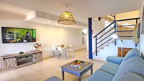 Una sala de estar moderna con sofá, mesa de centro, televisor y comedor.
