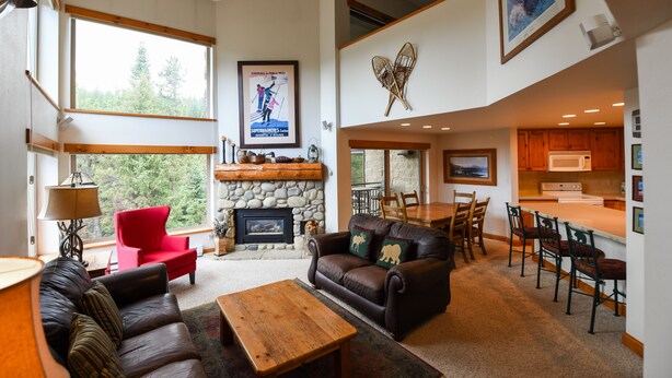 A spacious living area with a fireplace, a red chair, a brown leather sofa, and a wooden coffee table.