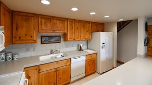 A kitchen with wooden cabinets, a white refrigerator, and a dishwasher.