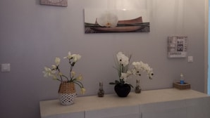 Een modern interieur met een grijs kastje, decoratieve vazen en wanddecoratie.