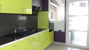 Een keuken met groene kastjes, een zwart aanrecht en een raam.