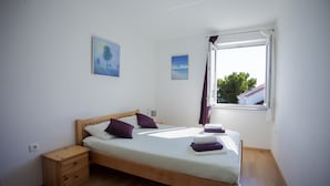 Una cama individual con cabecera de madera, una mesita de noche y una ventana con cortinas.