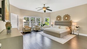 A bedroom with a large bed, a ceiling fan, a desk, and a window with a view of greenery. - Plantation Point: Family Friendly Neighborhood (Plantation)