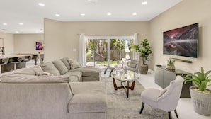 A modern living room with a sectional sofa, a glass coffee table, and a white armchair. - Plantation Point: Family Friendly Neighborhood (Plantation)