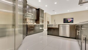 A modern kitchen with stainless steel appliances, dark cabinetry, and a tiled backsplash. - Plantation Point: Family Friendly Neighborhood (Plantation)