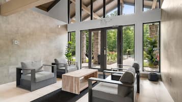 A modern interior with a sofa, armchairs, and a coffee table. Large windows provide views of the outdoors.