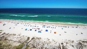 Ein Strand mit vielen Sonnenschirmen und Liegestühlen, ein sandiger Uferstreifen und das Meer.