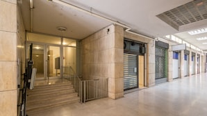Entrada de la edifici moderna amb porta de vidre, escala i reixatge metàl·lic.