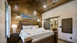 Un dormitorio con paneles de madera, una cama grande, una mesita de noche, una lámpara y un espejo.