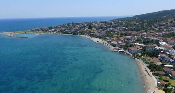 Vue aérienne d’une ville côtière, avec une mer bleue et limpide, une plage et des immeubles d’habitation.