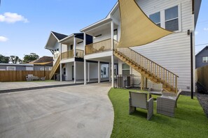 Ein zweistöckiges Haus mit überdachter Veranda, einer Treppe und Gartenmöbeln.