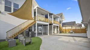 Une maison à deux étages avec un patio couvert, une clôture en bois et une pelouse verdoyante.
