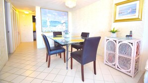 Uma área de refeições com mesa de vidro, cadeiras pretas e um armário branco com design vazado.
