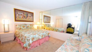 Um quarto com uma cama, mesa de cabeceira, penteadeira, espelho e um quadro na parede.