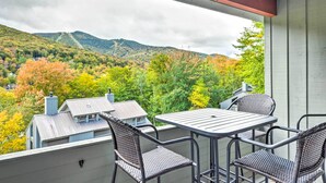 Uma varanda com mesa e cadeiras oferece uma vista panorâmica de árvores e colinas com tons de outono.