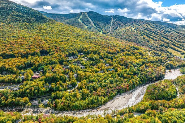 A mountainous landscape with a river, houses, and a winding road.