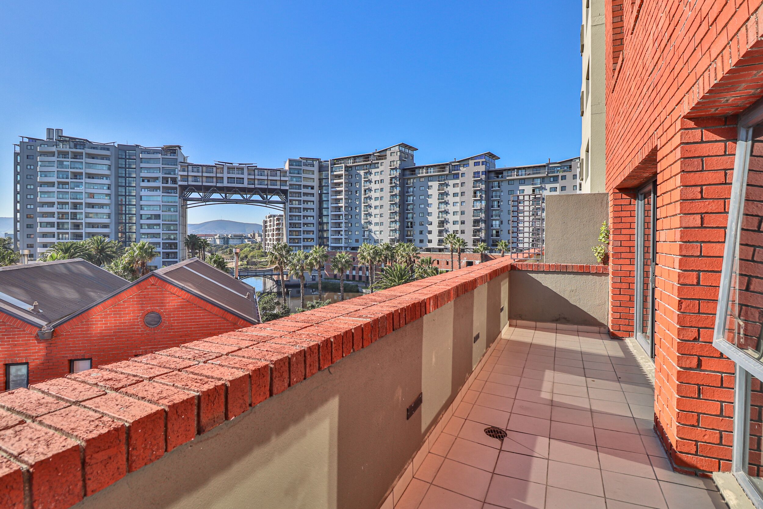 A high-rise residential building with a red brick exterior and a tiled balcony.