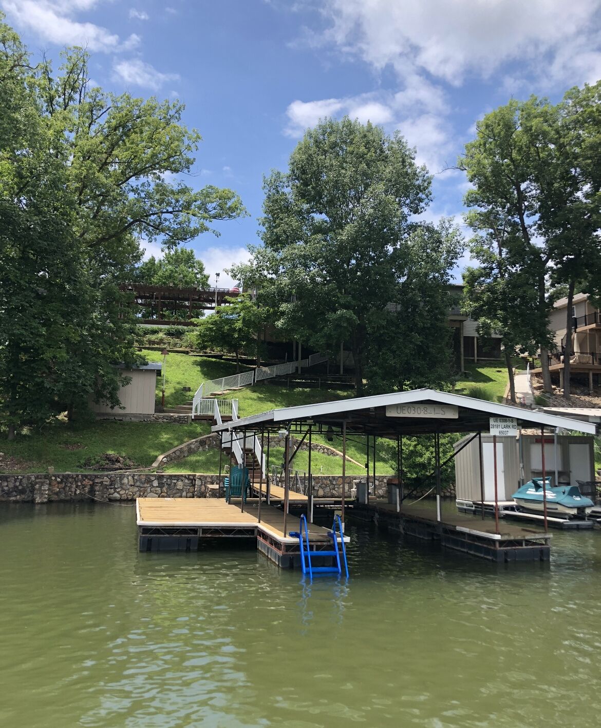 A dock with a covered area, a boat, and a small building with a sign.