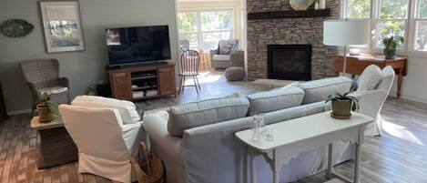 Una sala de estar con chimenea de piedra, televisor y zona de estar acogedora.