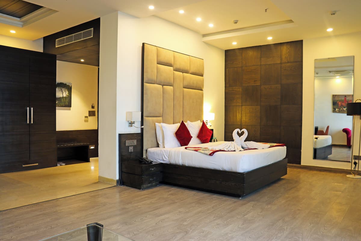 A modern hotel room with a large bed, a wardrobe, and a mirror.