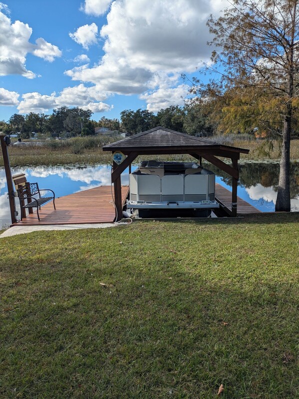 A gazebo with a barbecue grill, a bench, and a wooden deck over water. - Waterfront lake home w/  fishing, boating, & water activities! (Inverness)